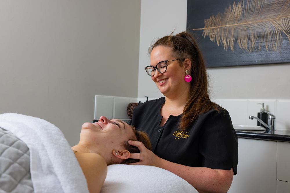 Laura working as a beauty therapist giving a client a head massage.